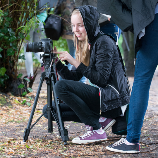 Jugendliche fotografiert mit einer Kamera auf Stativ bei einem Herbstferien-Workshop