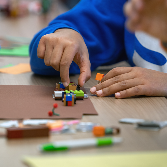 Kinderhände bewegen LEGO-Figuren für einen Trickfilm-Workshop am Kindergeburtstag