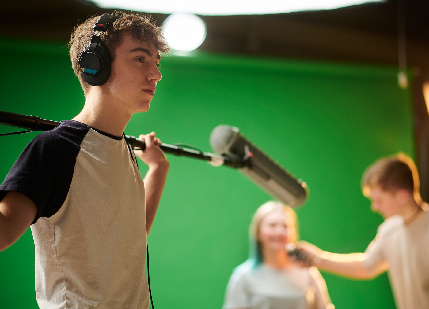 Jugendlicher hält eine Mikrofon-Angel im Greenscreen-Studio bei einem Medienprojekttag