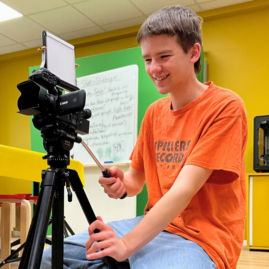 Freiwilligendienstleistender filmt mit einer Videokamera in einem Medienprojekt