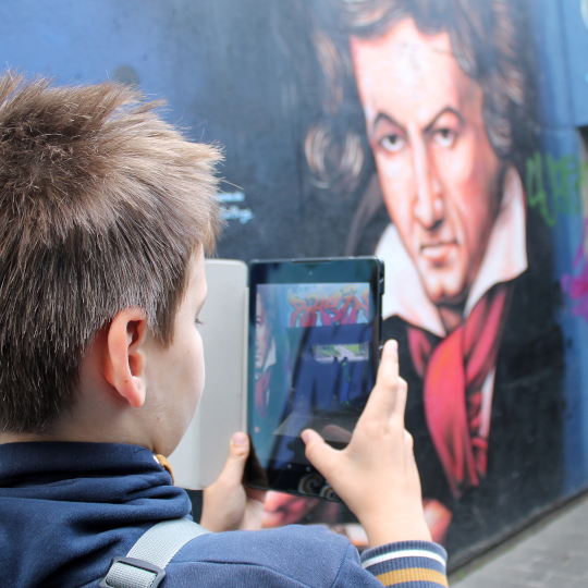 Junge fotografiert eine Beethoven-Wandmalerei bei einem Medienprojekt im Beethoven-Haus Bonn