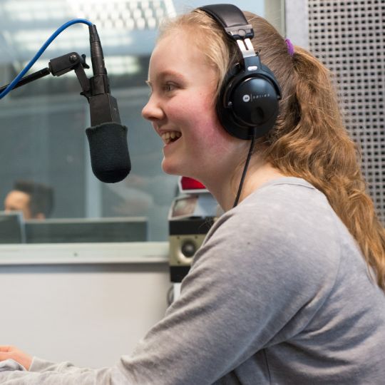 Ein Mädchen spricht in ein Studio-Mikrofon im Audio-Workshop