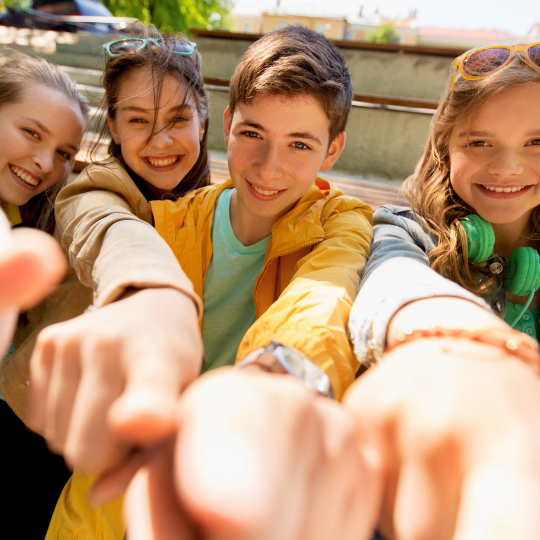 Vier Kinder zeigen mit dem Zeigefinger in die Kamera