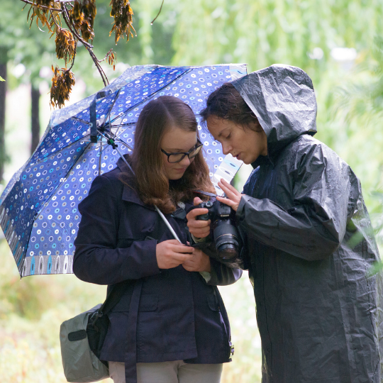 Zwei Frauen unter Regenschirm mit Fotokamera