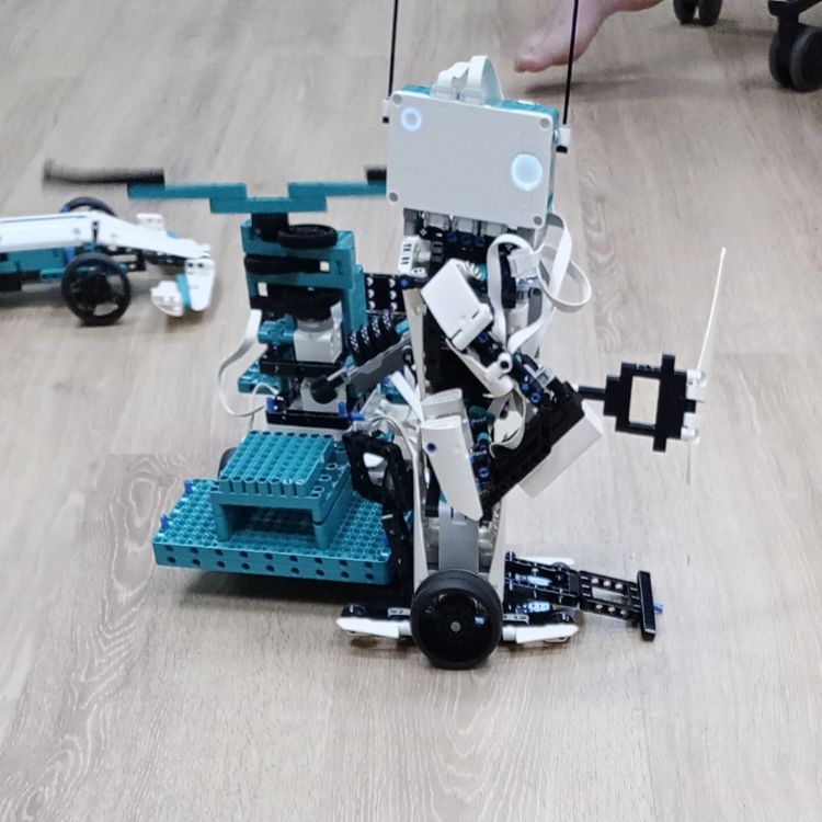 Junge Person baut einen Roboter mit LEGO Mindstorms auf einem Tisch mit Elektronikbauteilen.