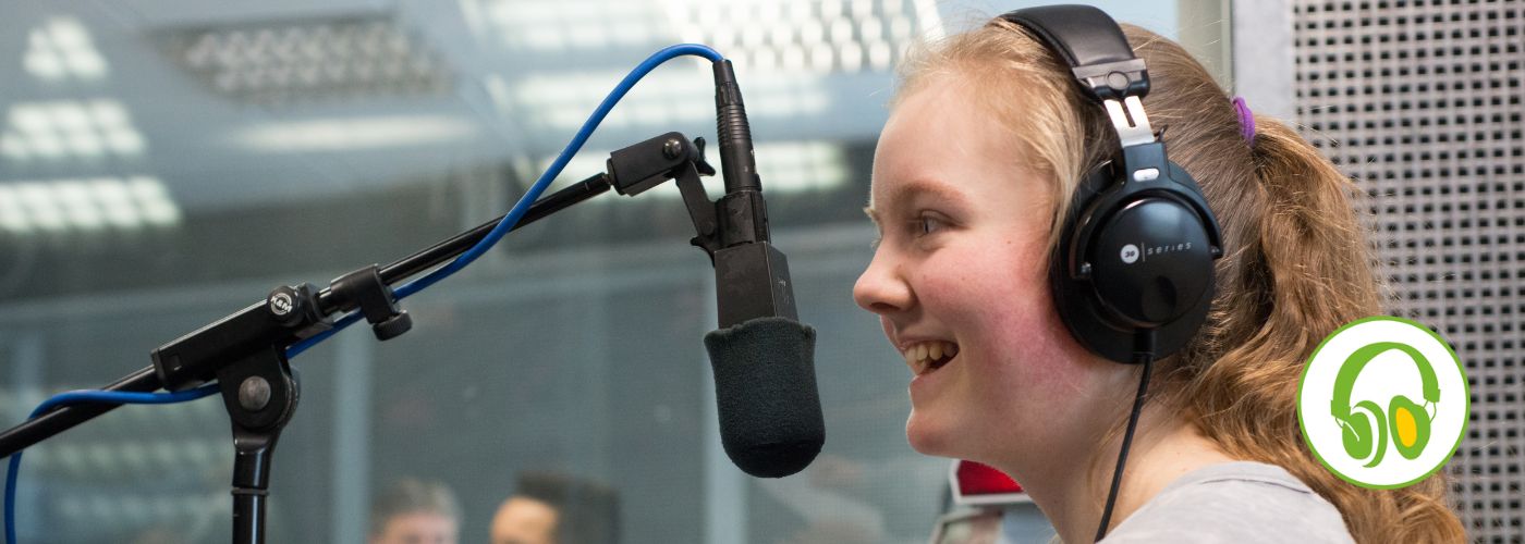Mädchen spricht im Tonstudio in ein Studiomikrofon bei der Aufnahme eines Hörspiels.